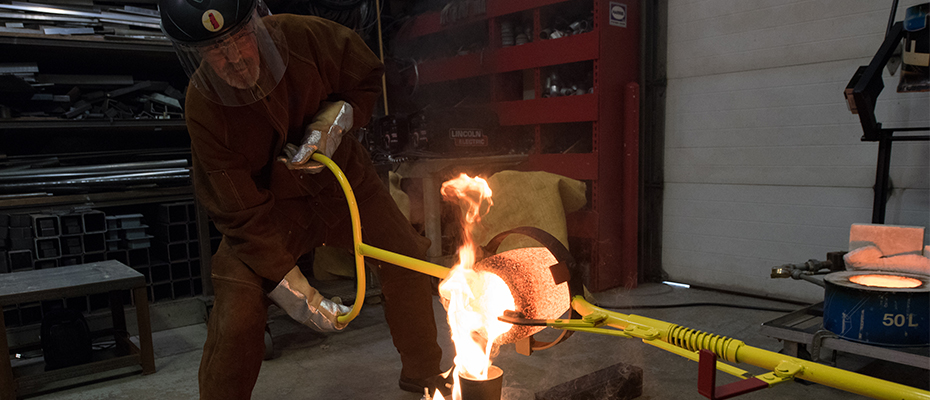 Bud Tucker pours hot bronze into brick mold